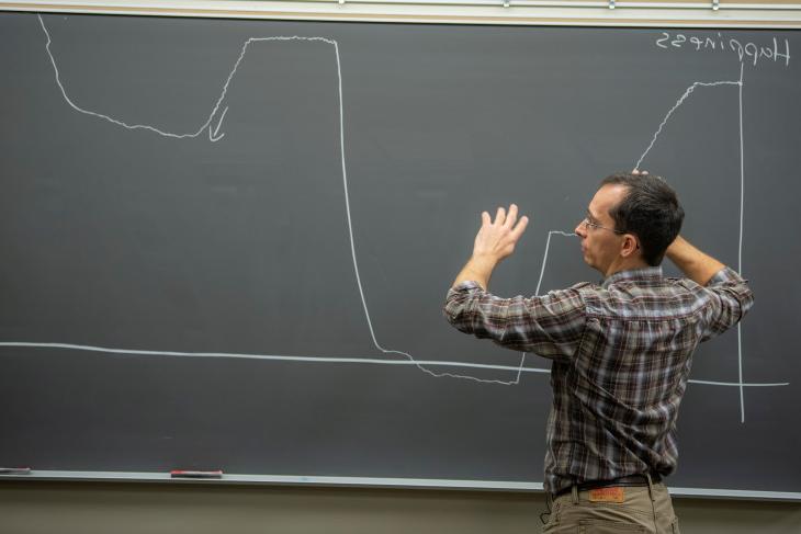 Professor Jacob Hale stands at a chalkboard 