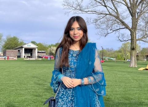 Zaheen dressed in a long blue dress with a sheer blue scarf draped over her shoulder.